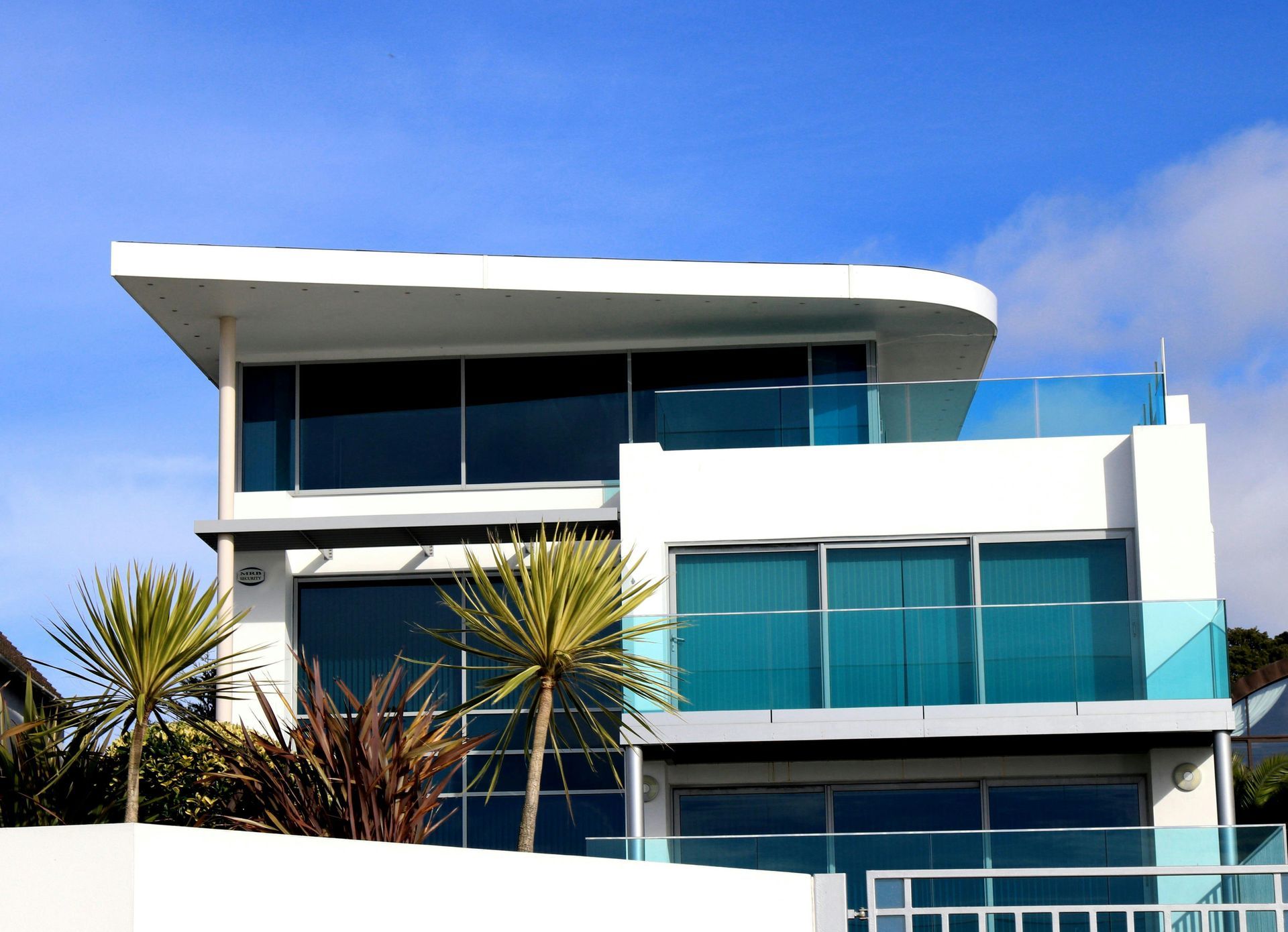 White modern house with large windows and blue accents under a blue sky.