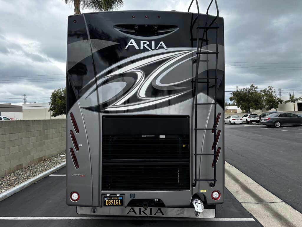 The back of a aria rv is parked in a parking lot.