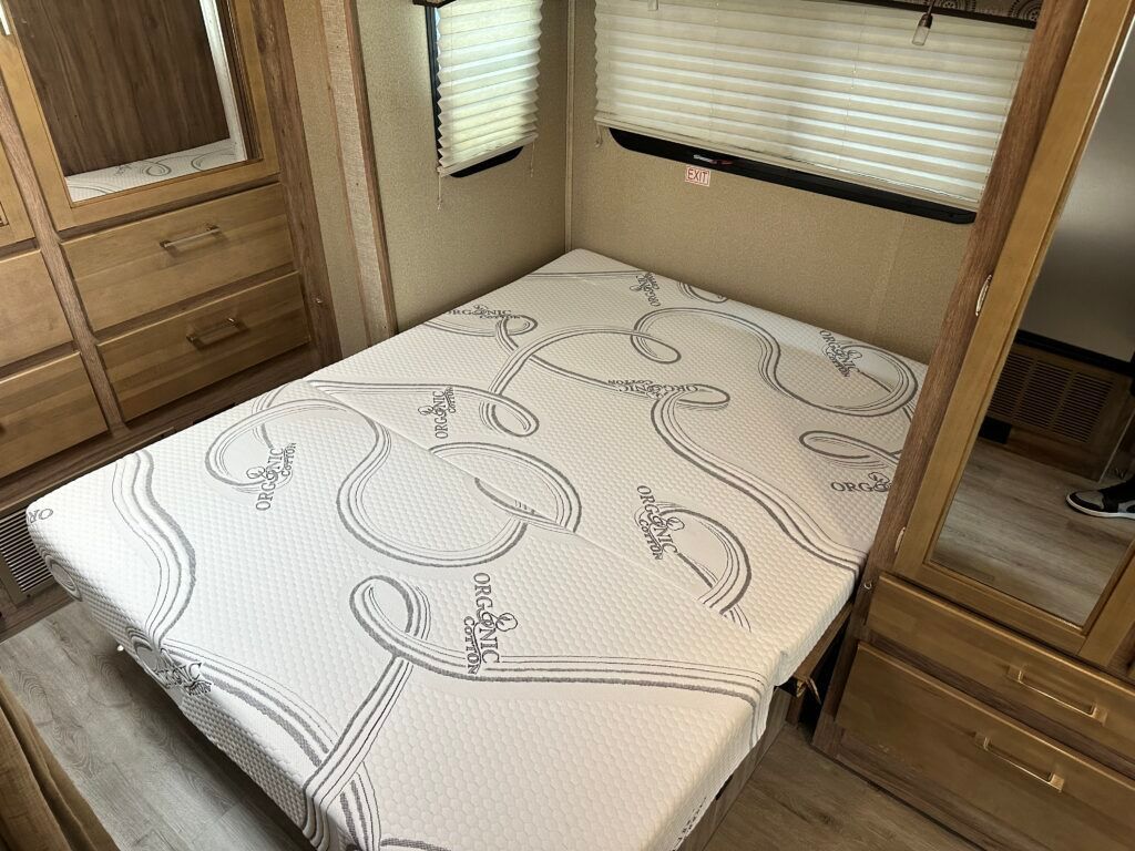 A bed with a mattress on it in a rv.