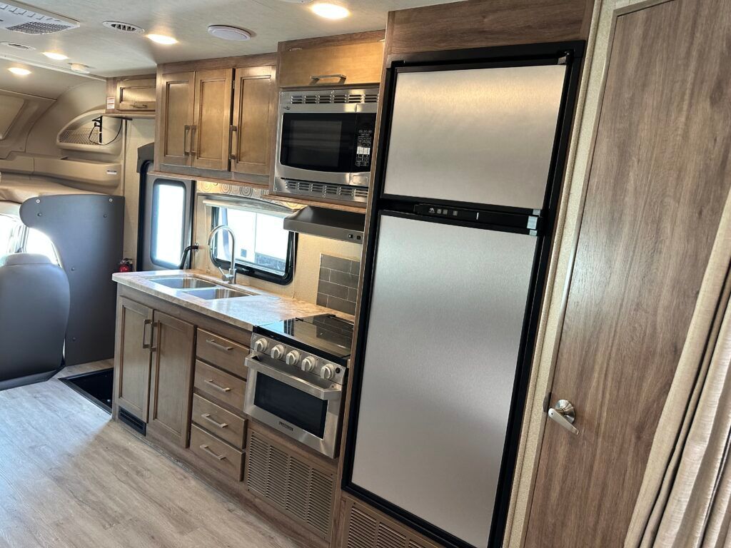 A kitchen in a rv with stainless steel appliances and wooden cabinets.