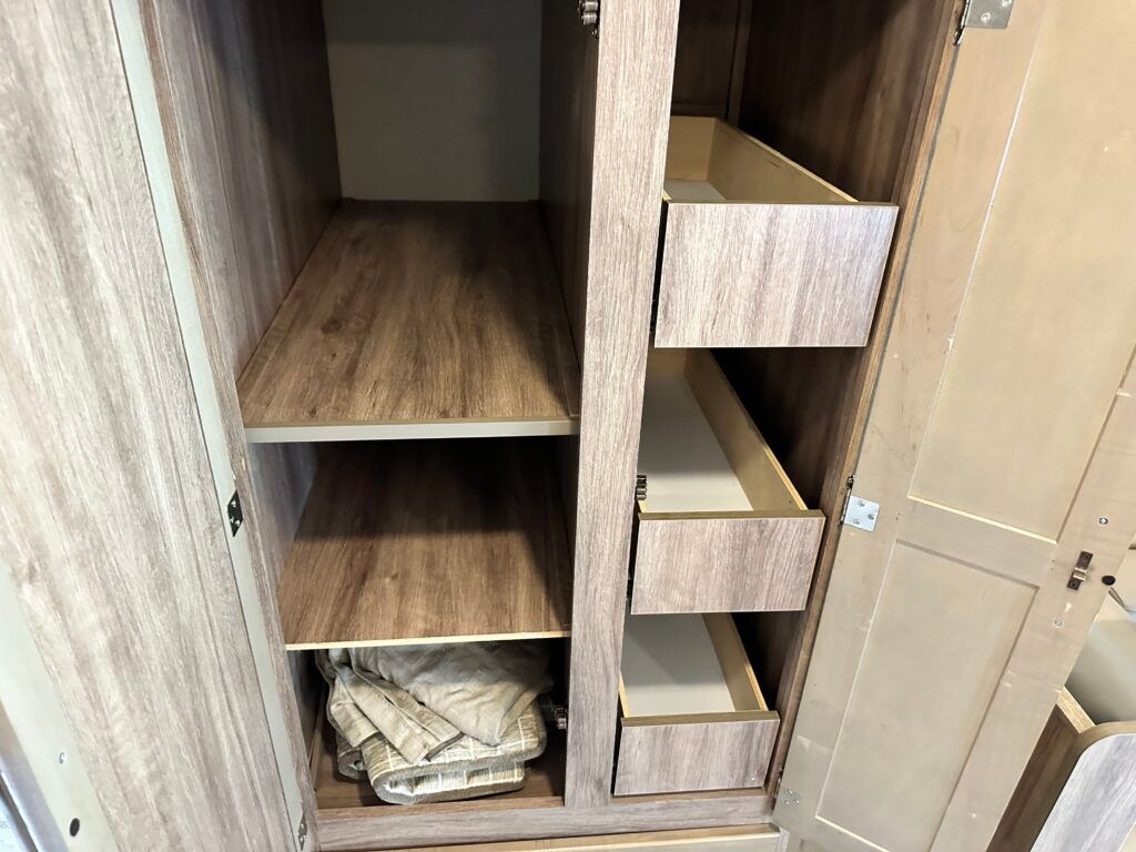 The inside of a wooden cabinet with drawers and shelves.