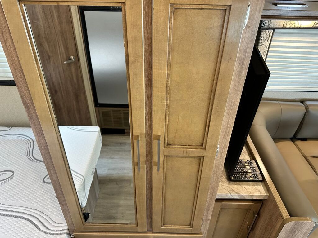 A wooden cabinet with a mirror on the doors in a bedroom.