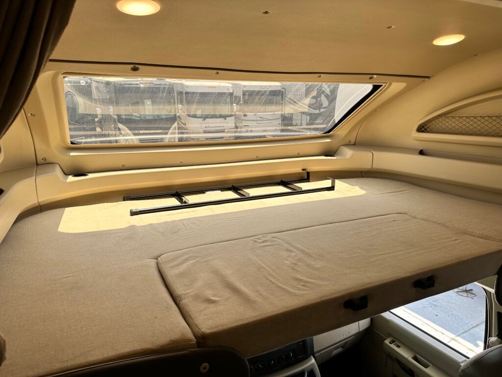 A bed in the back of a truck with a window above it.