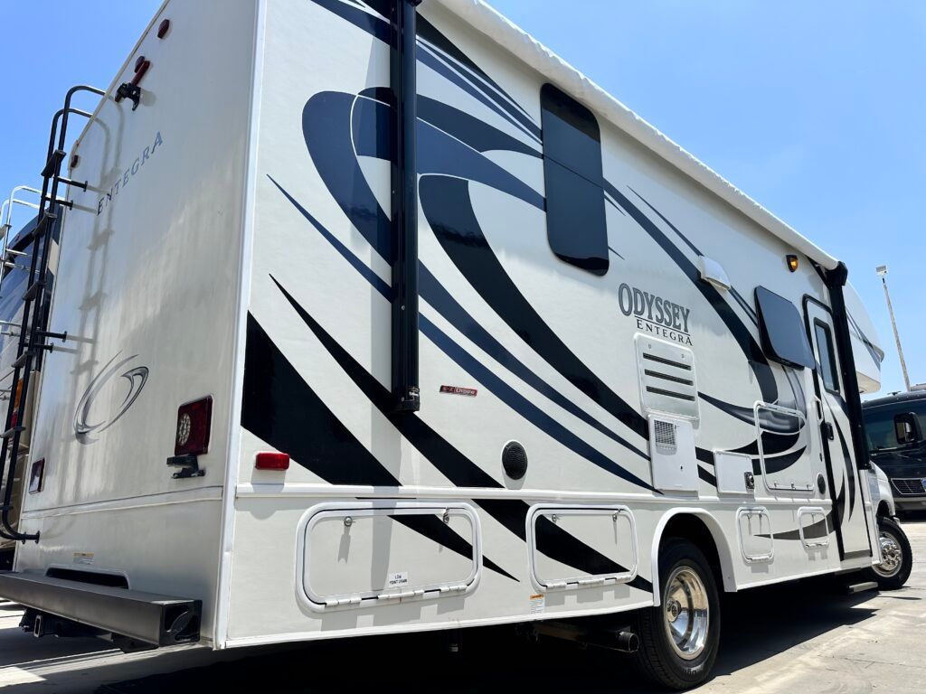 A white and black rv is parked in a parking lot.