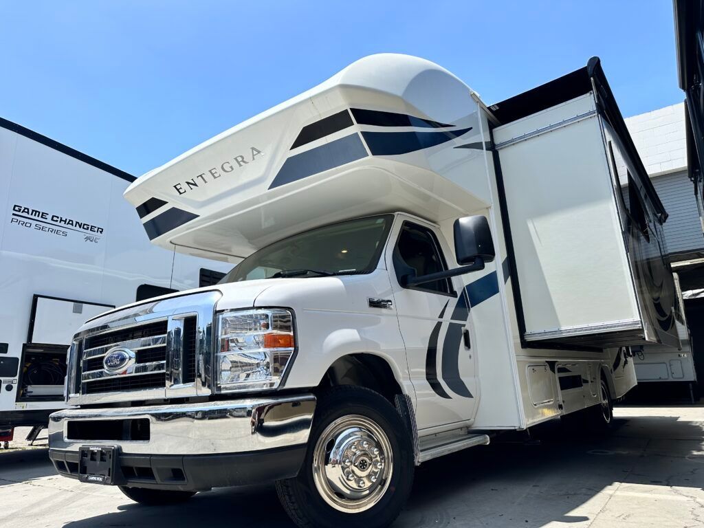 A white truck is parked in front of a building with its doors open.