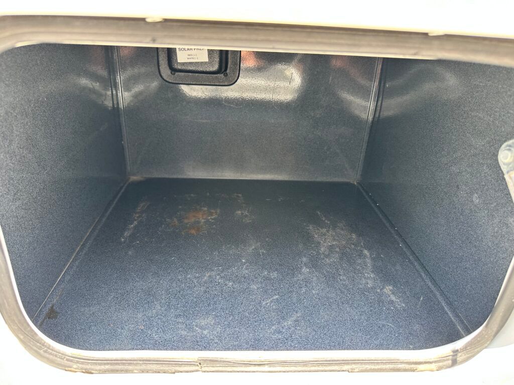 The trunk of a car is empty and has a gray carpet.