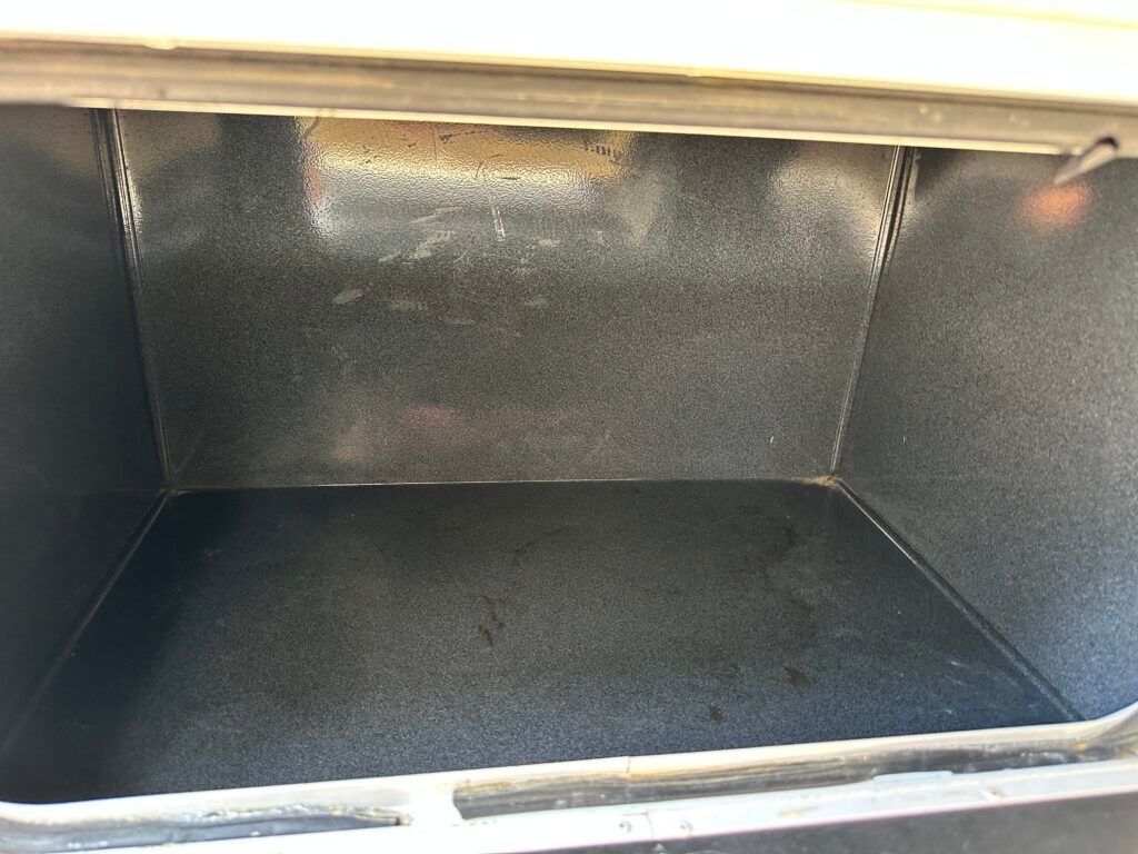 The inside of an oven is empty and looks like a trunk.