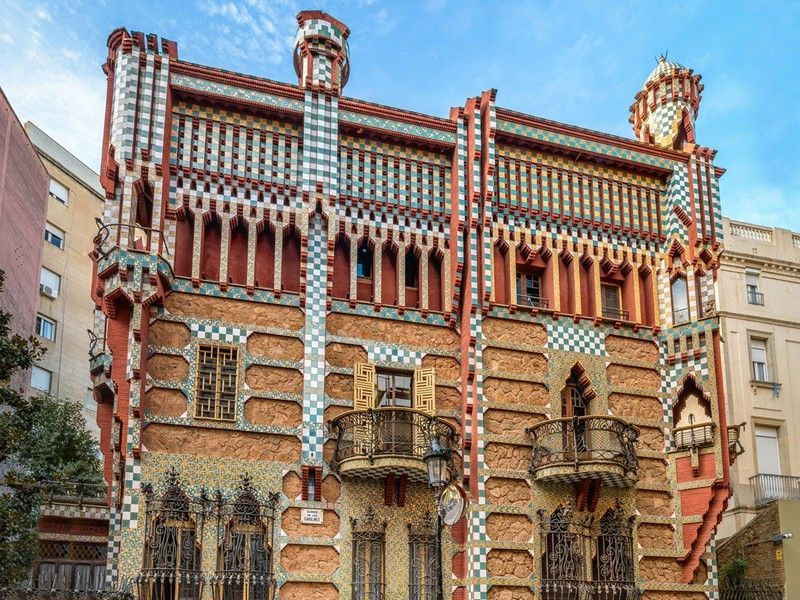 Ornate brick building with colorful striped facade and decorative balconies against a blue sky
