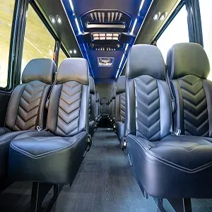 Inside a sleek black van, facing leather seats with chevron stitching and blue ceiling lighting