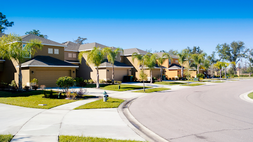 A beautiful suburban neighborhood and real estate with a row of modern, tan-colored houses featuring