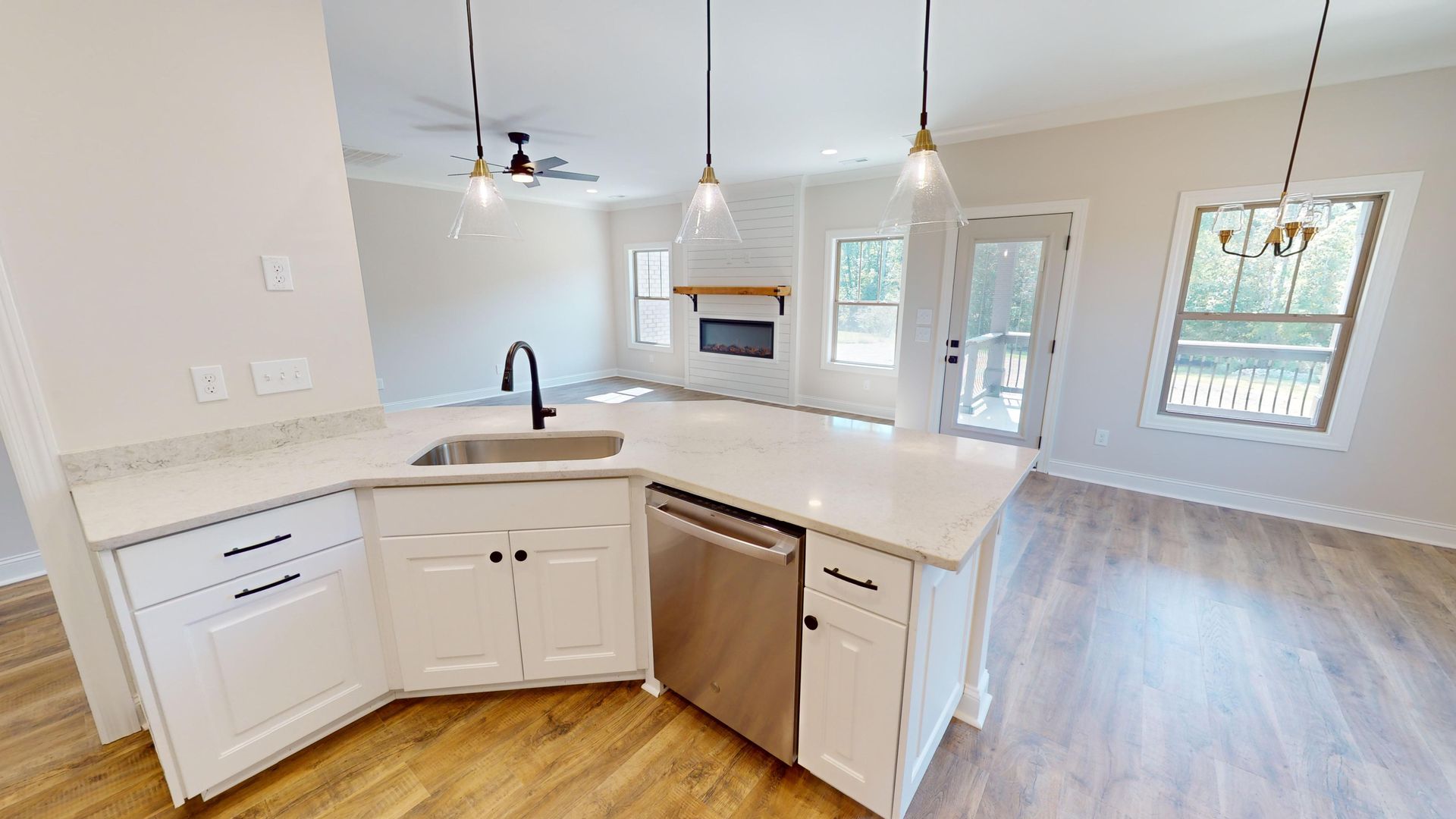 Modern kitchen with white cabinets, island with sink, and open view of living area.