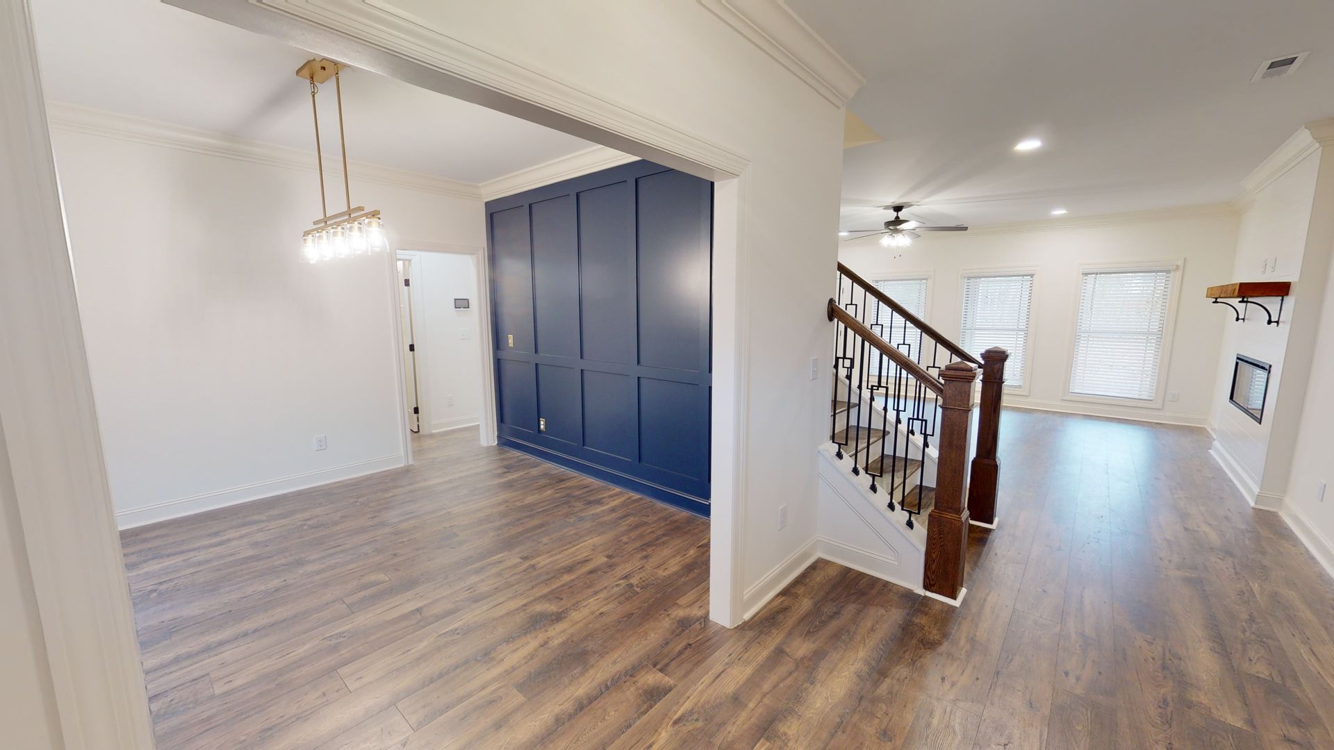 Interior view of a home with wood floors, blue paneling, and a staircase.