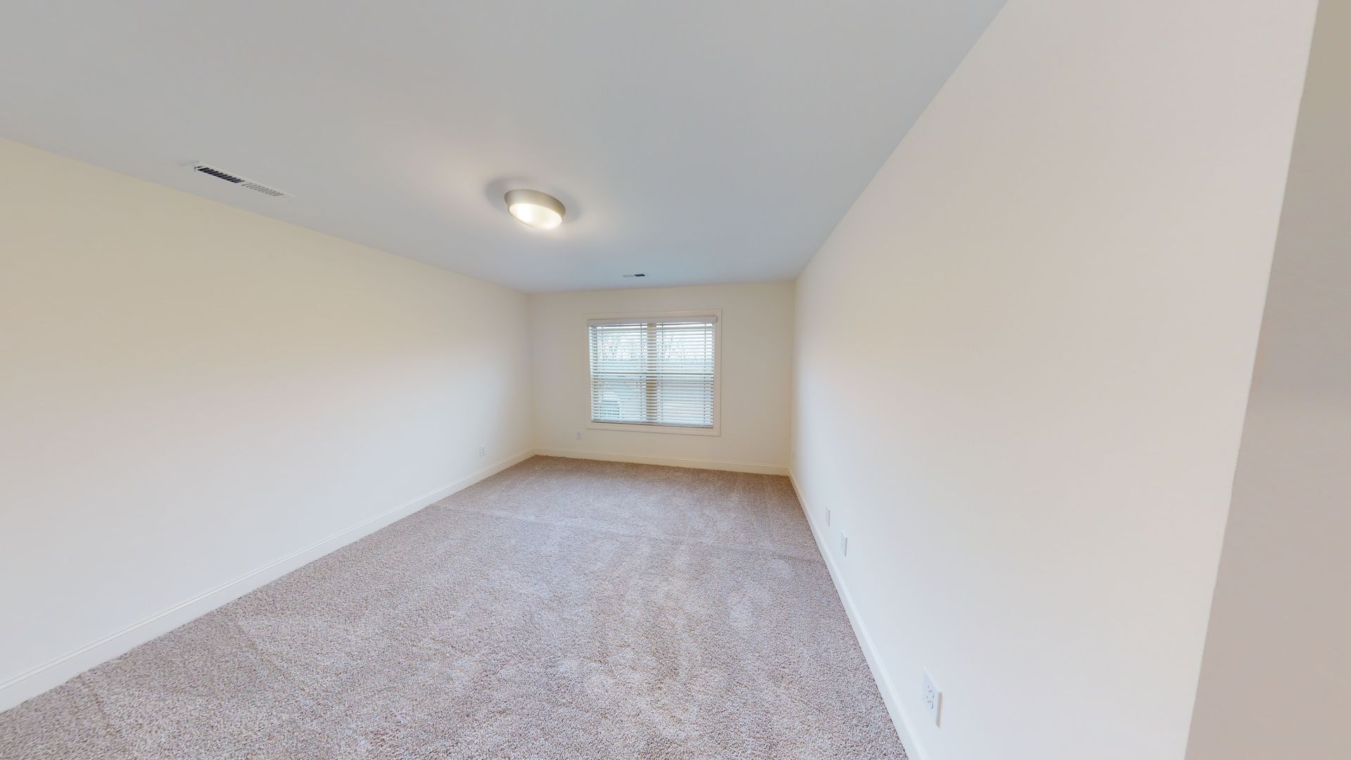 Empty room with beige walls, carpet, and a window.