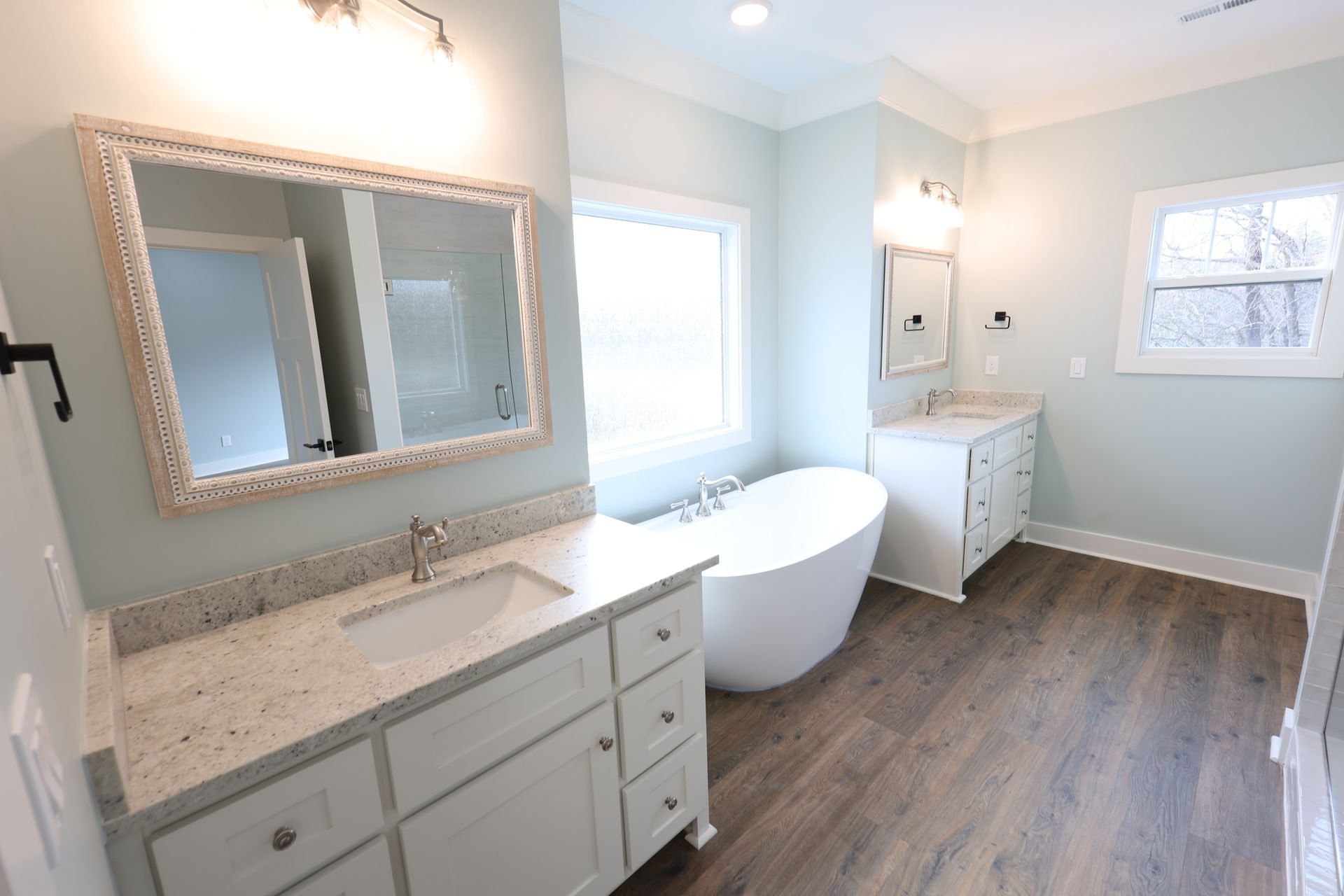 Bathroom with a white freestanding tub, two vanities, and light blue walls.