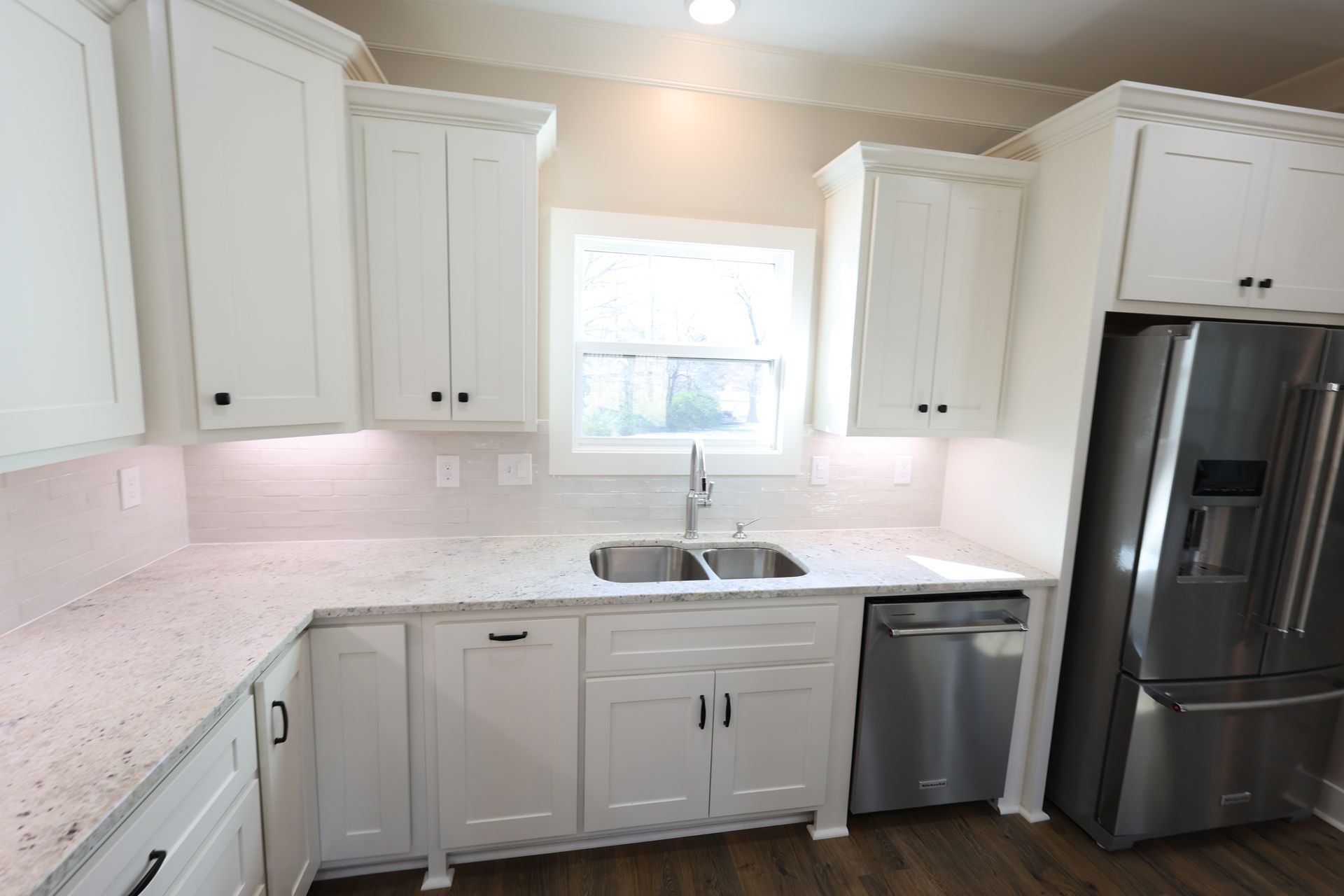 White kitchen cabinets, countertop, sink, and stainless steel appliances.
