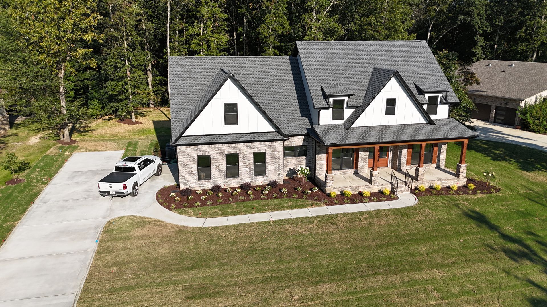 A two-story house with stone and white accents and a gray roof. A pickup truck is parked in the driveway.