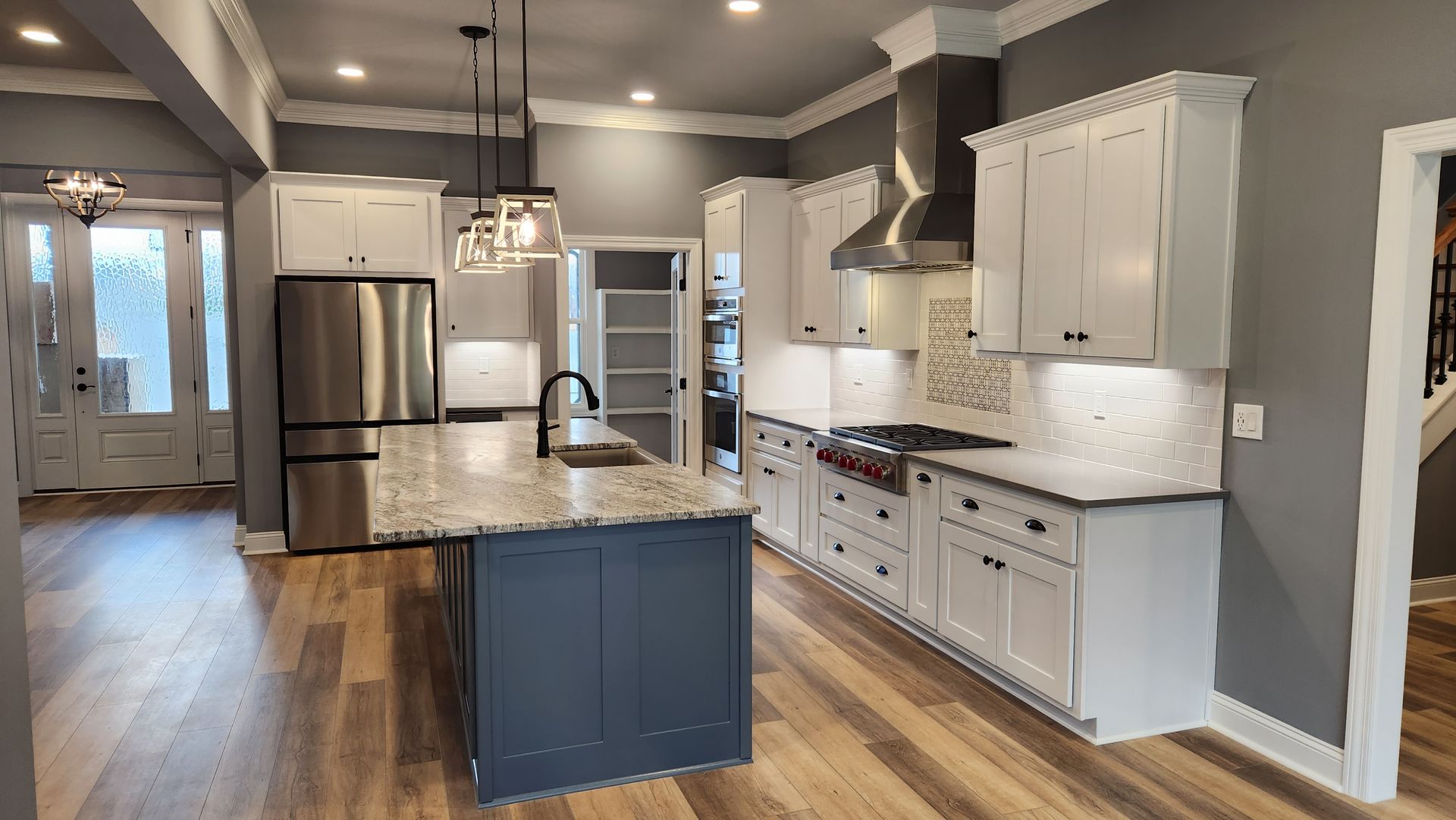 Modern kitchen with white cabinets, stainless steel appliances, and a gray island.