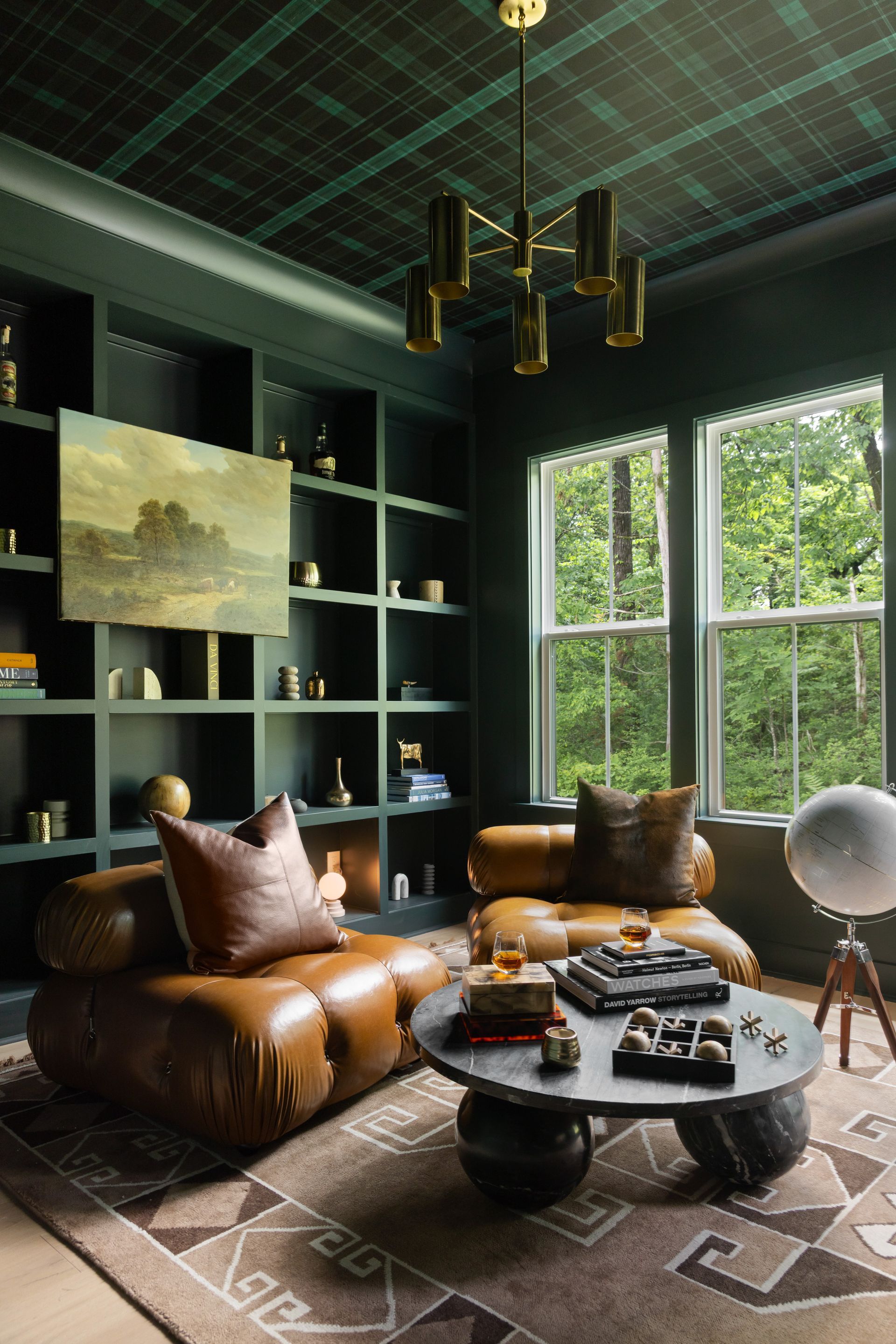 Cozy library with green walls, tartan ceiling, leather chairs, and a round coffee table