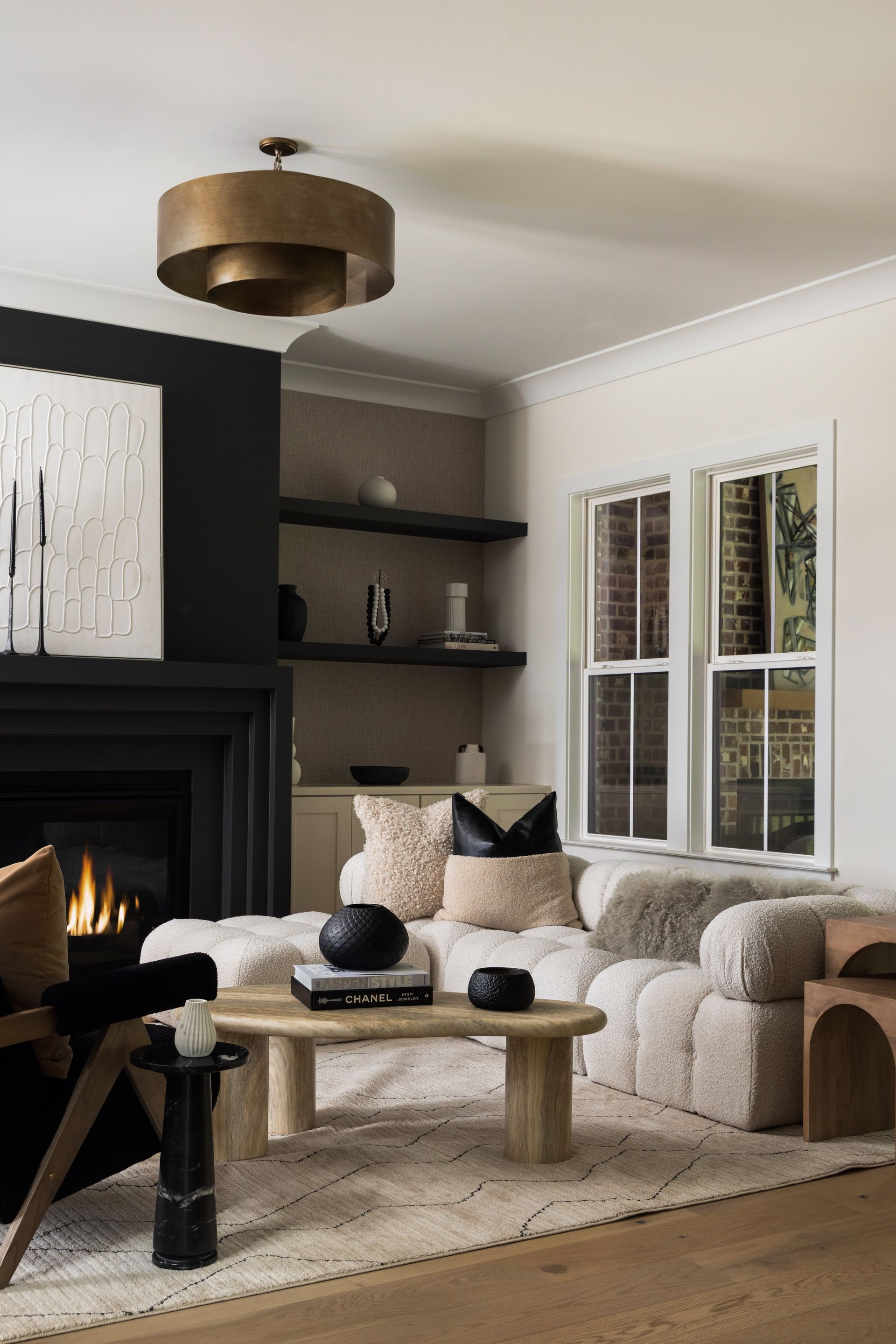 Cozy living room with black fireplace, white sofa, and a gold light fixture.