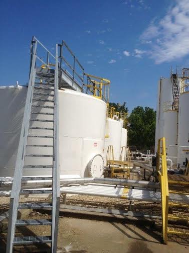 a ladder is sitting on top of a large white tank .