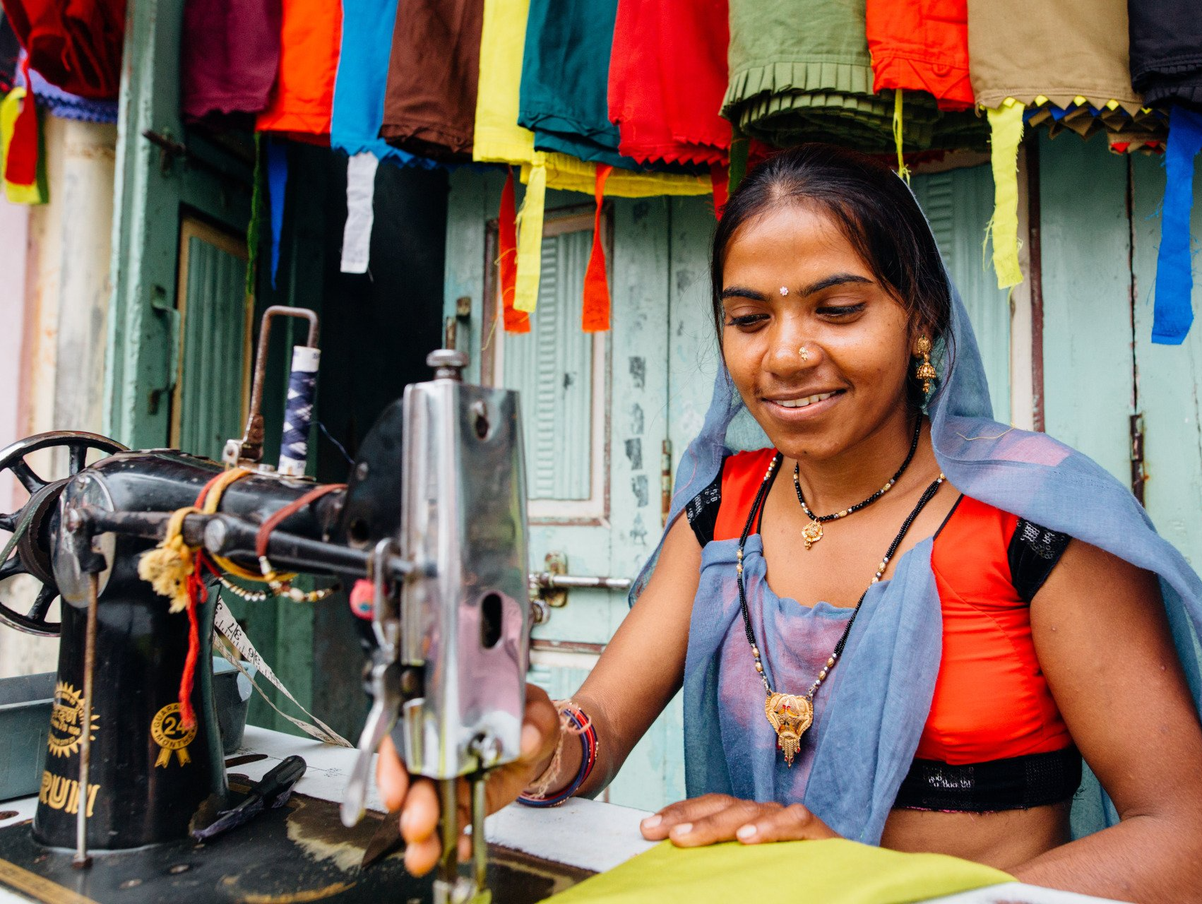 A woman is smiling while using a sewing machine