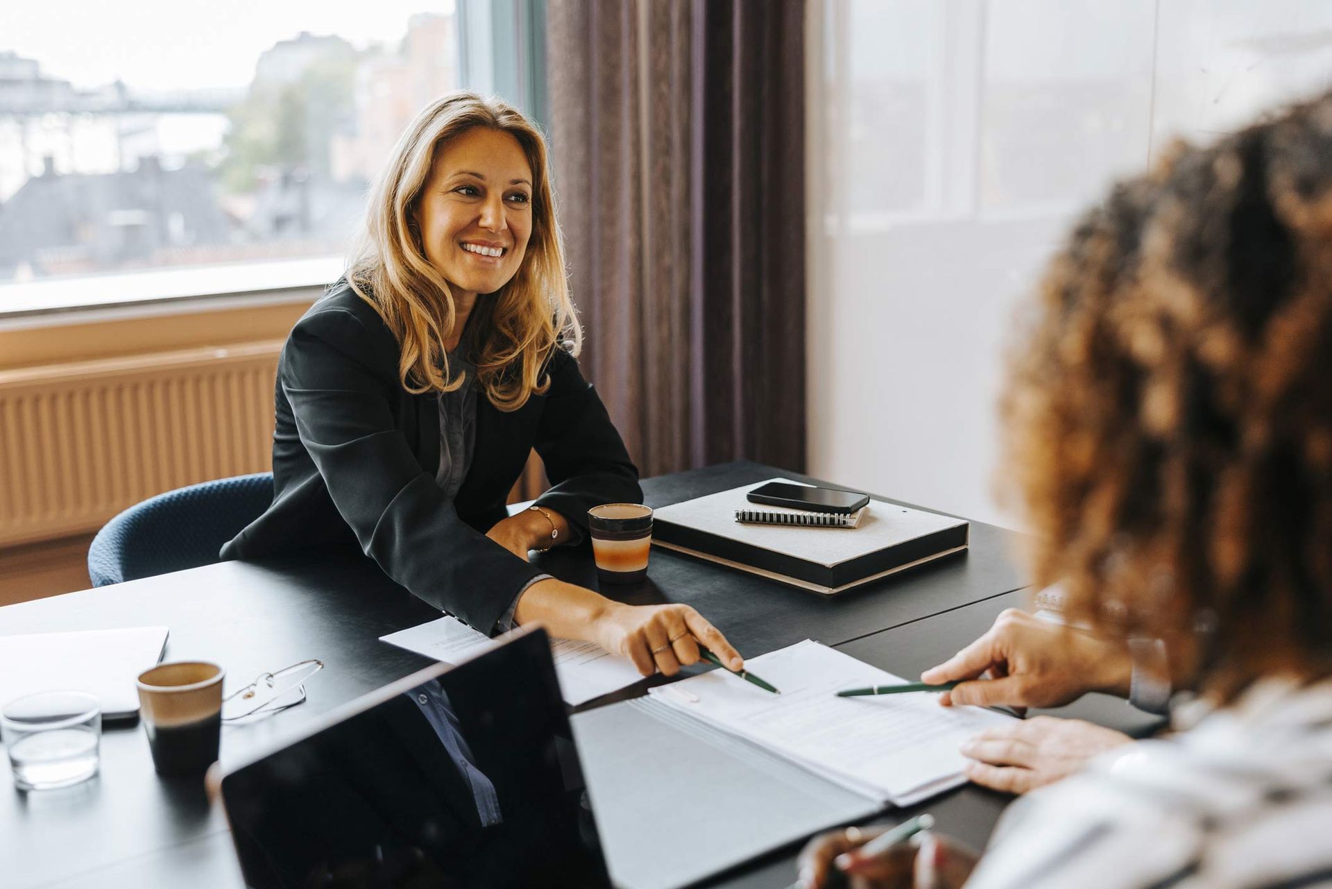 A woman is sitting at a table talking to another woman.