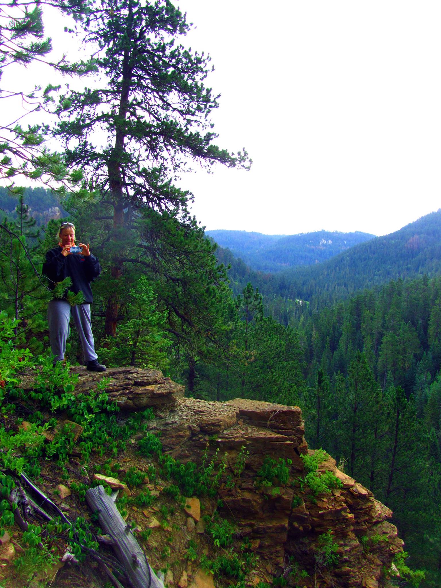 Woman taking a picture on top of a mountain