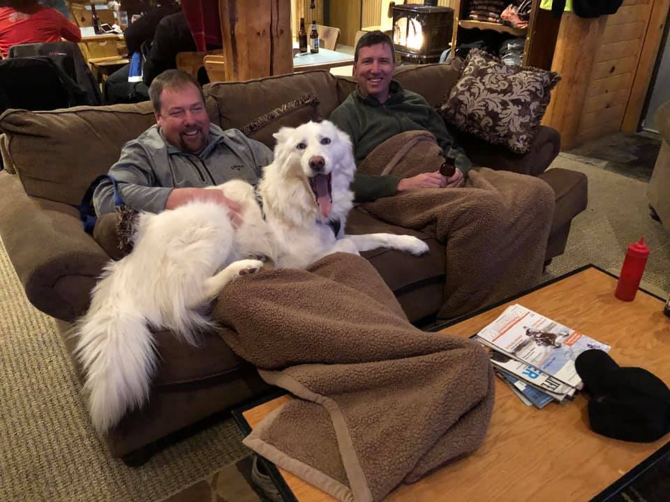 Two men sitting on couch with dog