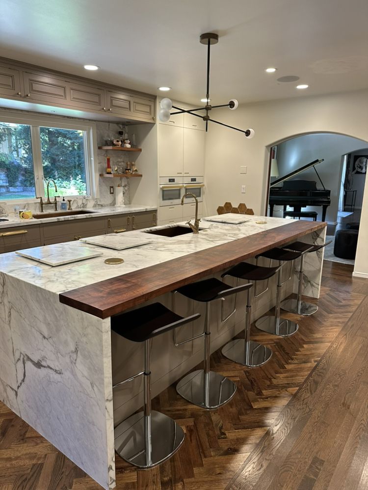 Modern kitchen with a large marble island, a dark wood countertop, and bar stools.