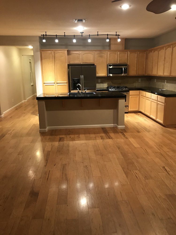 Spacious kitchen with light wood cabinets, dark countertops, and hardwood floors.