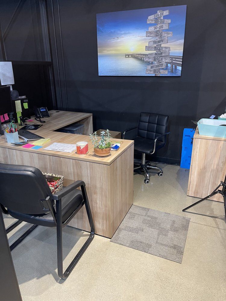 Office space with a large desk, black chairs, and a landscape painting.