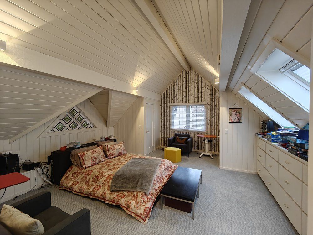 Bedroom with sloped ceiling, skylight, bed, and decorative birch-tree wall.