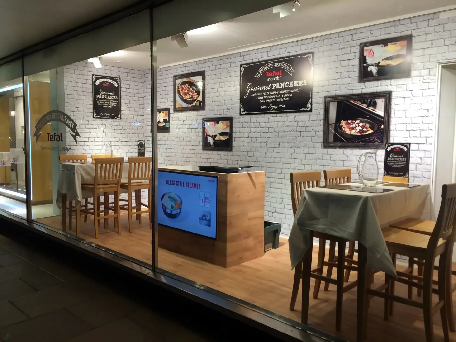 An event demo restaurant in a window with a table and chairs created and installed by Absolute Events
