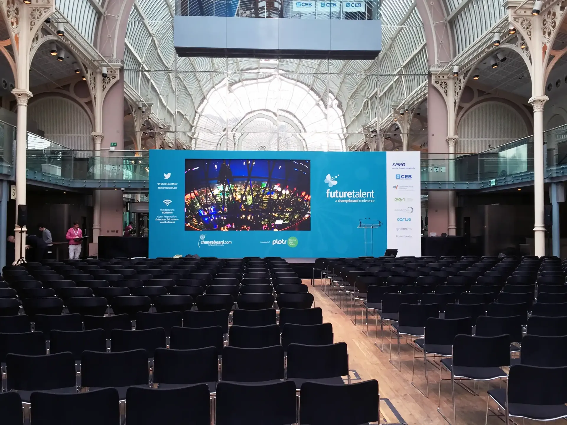 A large auditorium with rows of chairs and a large screen, provided by Absolute events