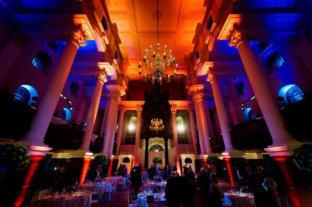 A large room with tables and columns is lit up with red and blue lights supplied by Absolute Events