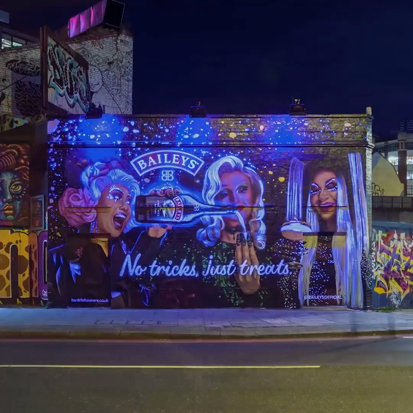There is a mural on the side of a building that is illuminated Absolute Events with UV light