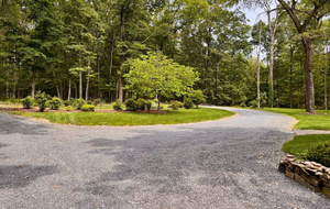Curving gravel path through a green wooded park with trees and flower beds
