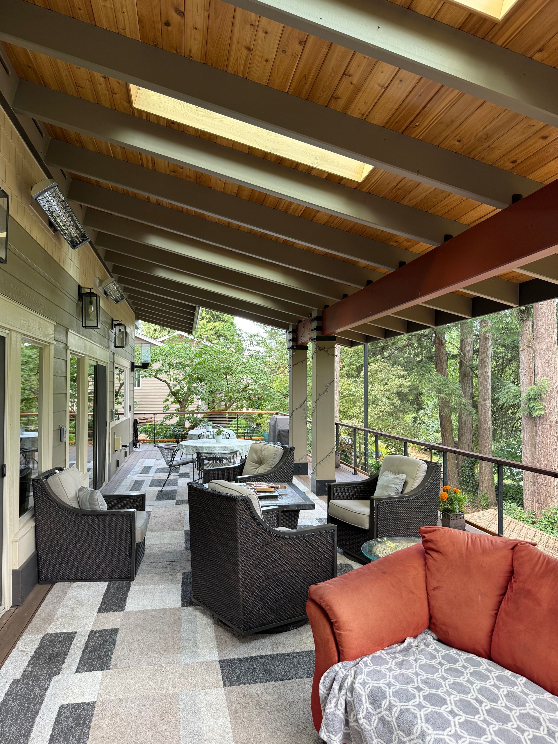 Covered outdoor deck with wood ceiling and lounge seating at Dearey Residence in Washougal, WA