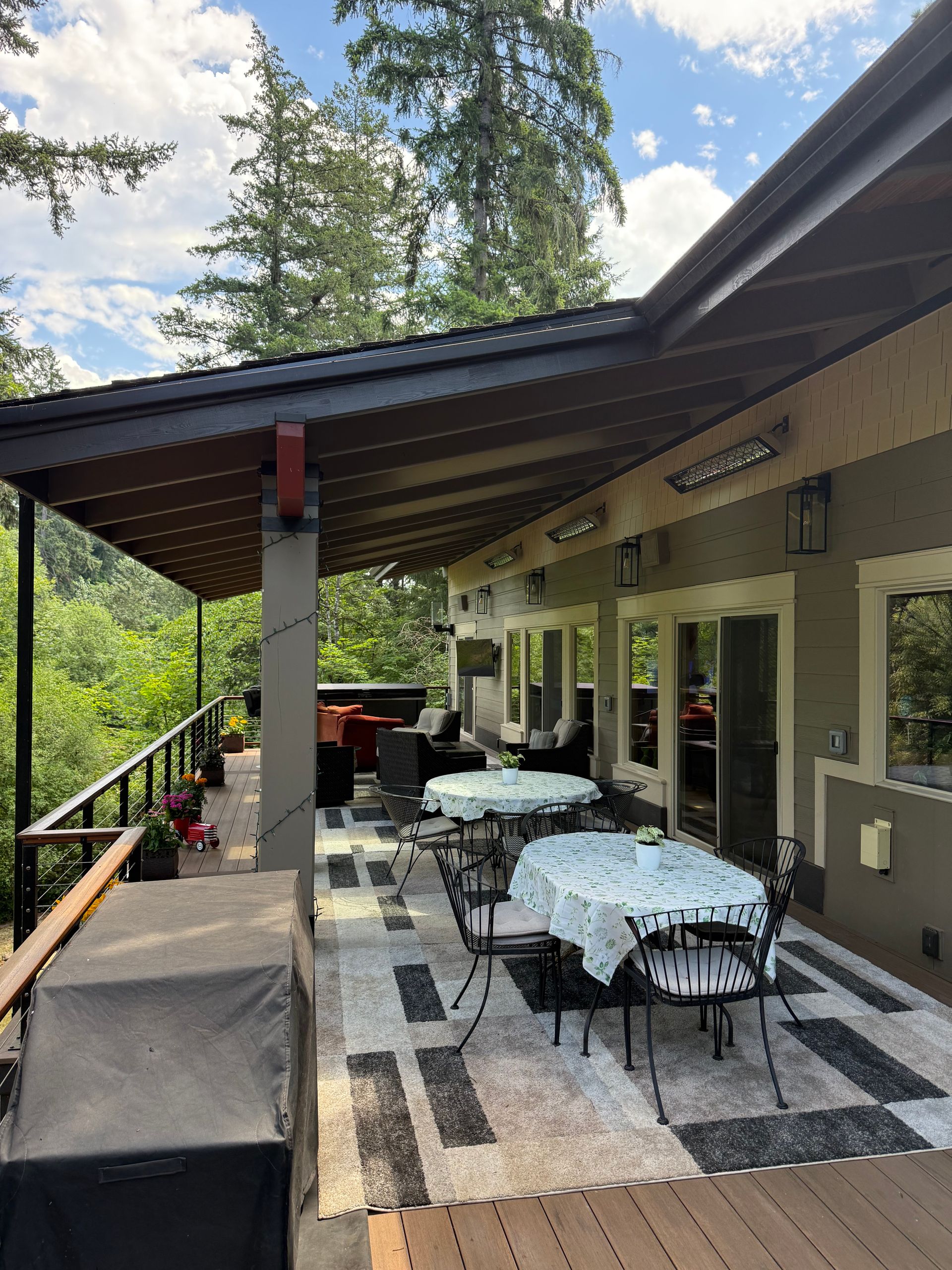 Covered deck dining space with patterned tile flooring at Dearey Residence in Washougal, WA