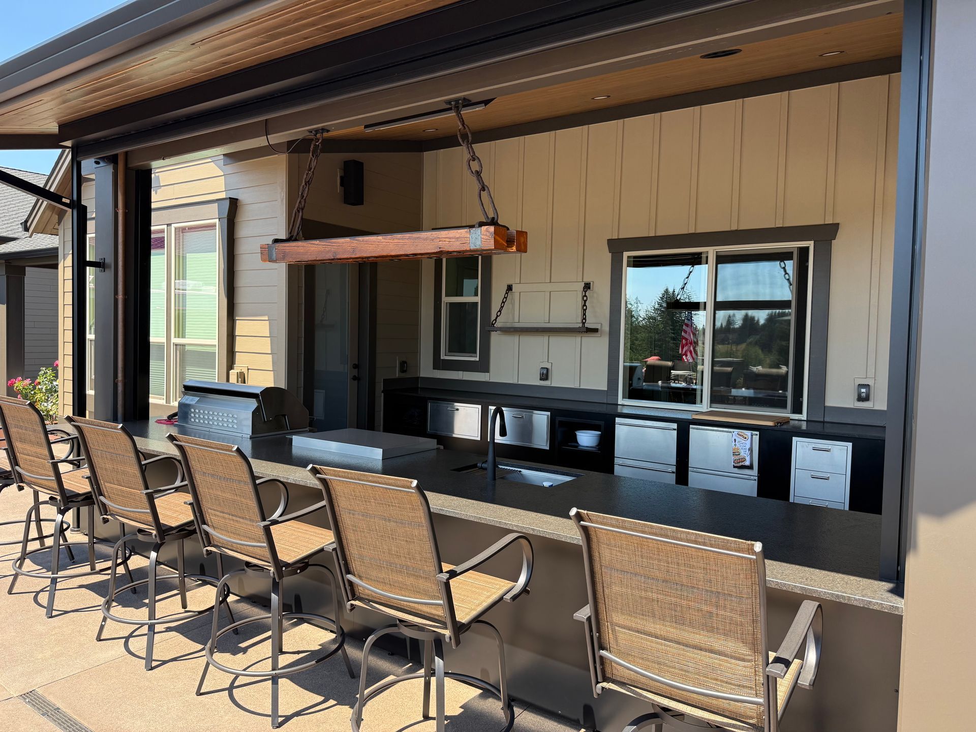Covered outdoor kitchen and bar with a built-in grill, seating, and custom cabinetry
