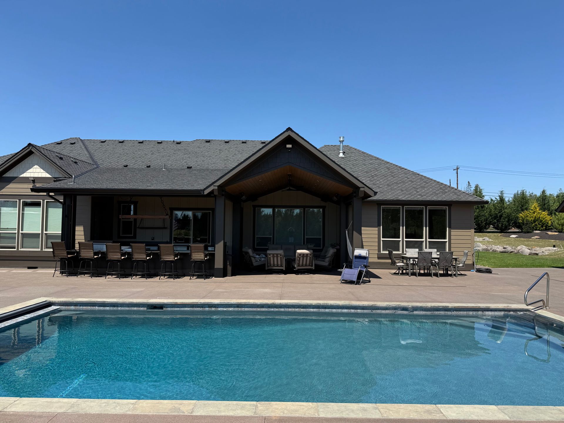Backyard view of a custom pool house with a swimming pool and covered outdoor living spaces