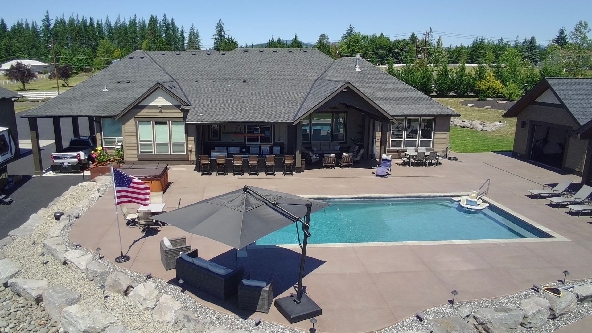Aerial view of a backyard swimming pool, custom pool house, and outdoor entertainment area in Washougal, WA.