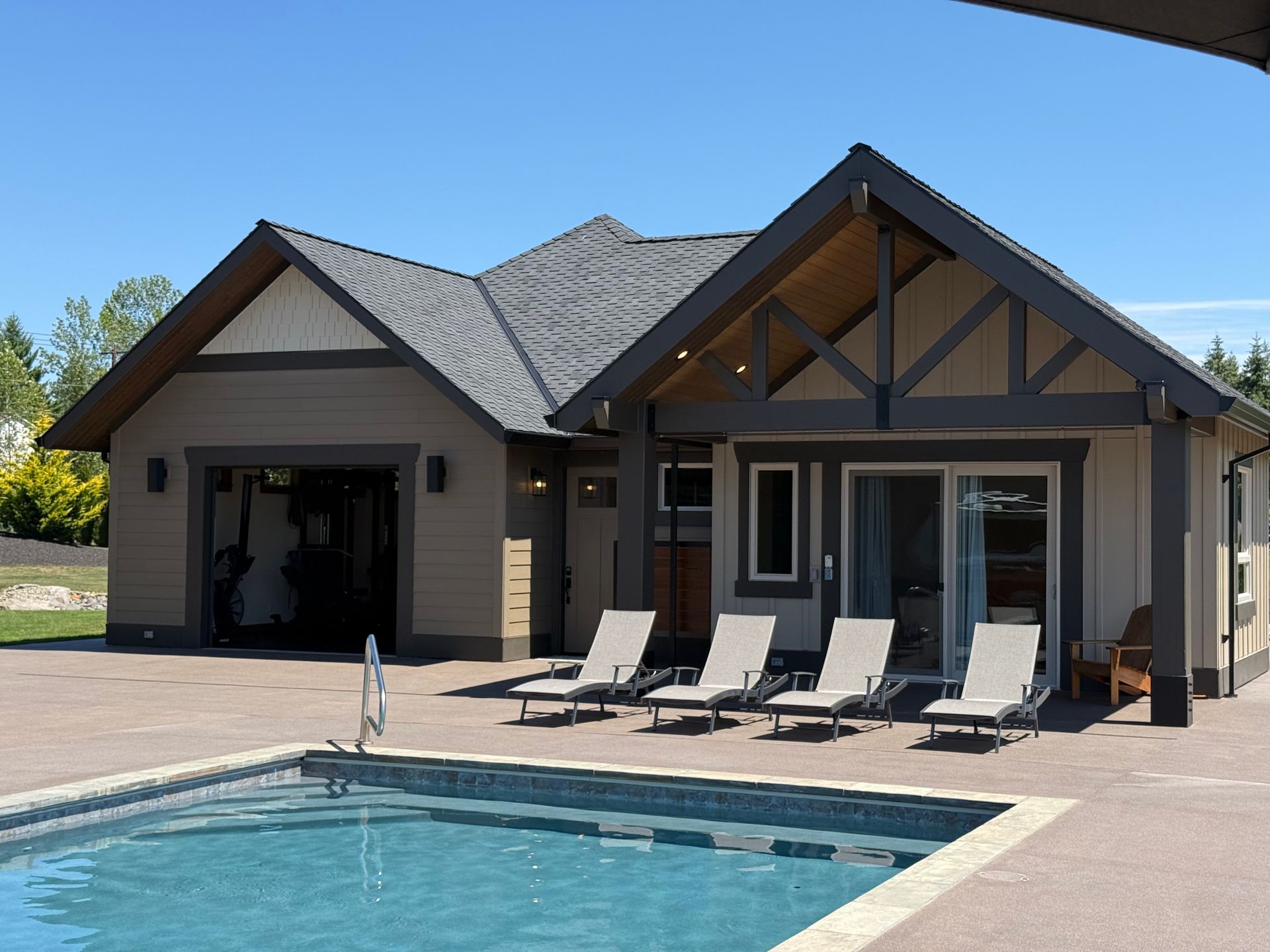 Custom pool house with exposed timber trusses, covered patio, and in-ground swimming pool