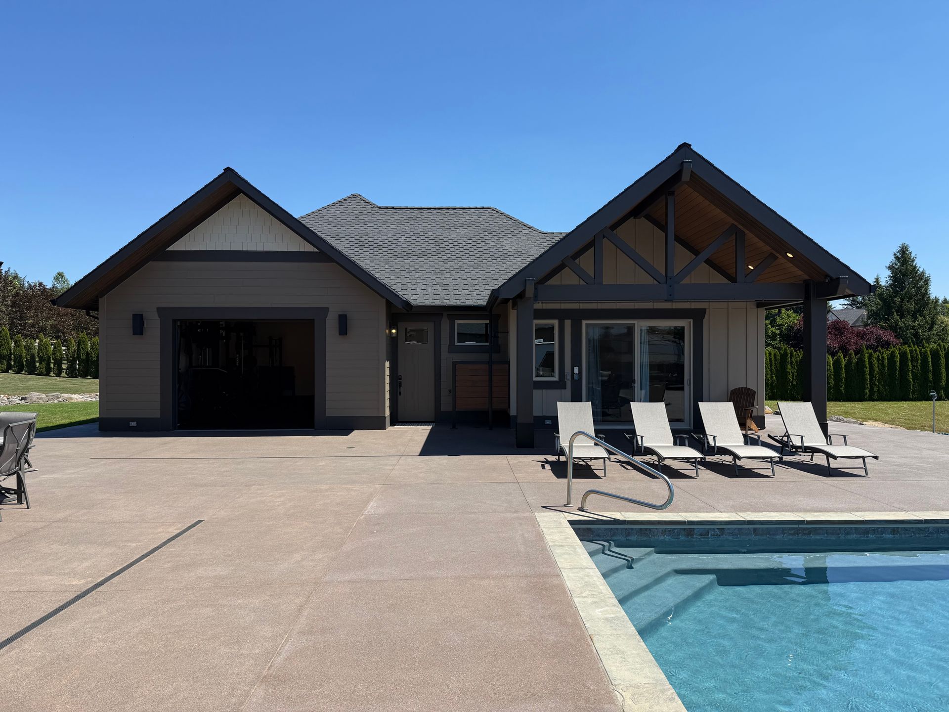 Modern pool house exterior with an attached garage and poolside lounge area in Washougal, WA.