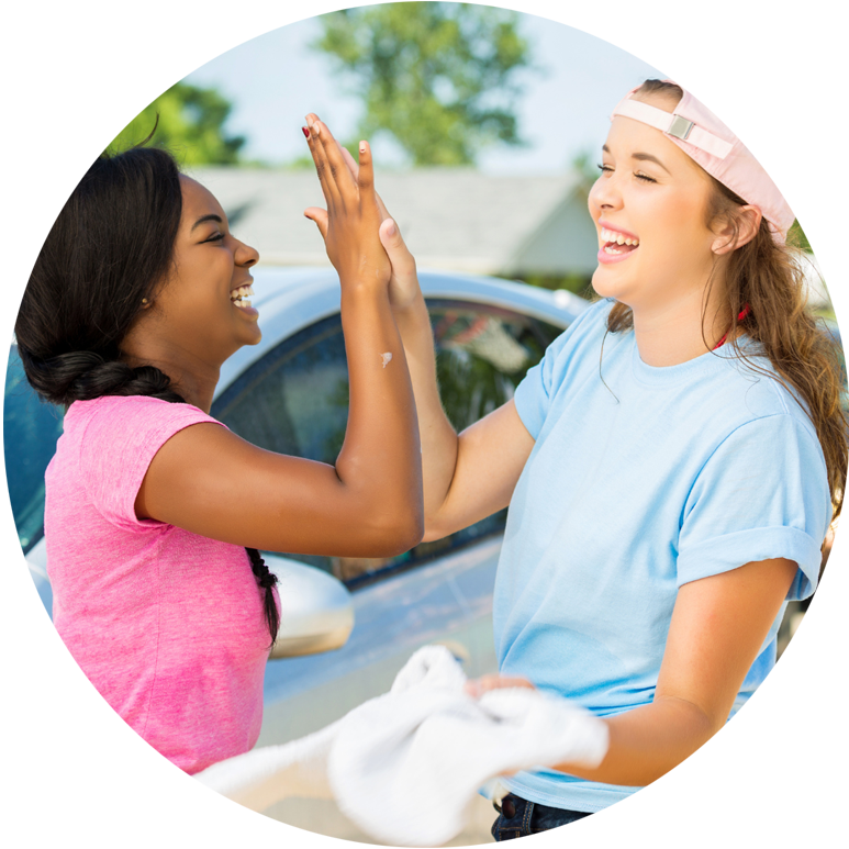 Two young female friends giving a high five at the park.
