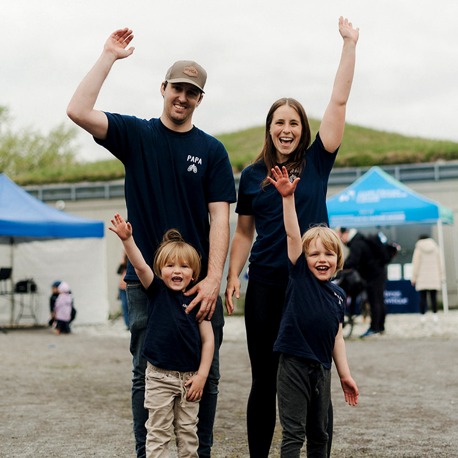 Mom, Dad and their two kids hold their arms up in celebration at The Walk.