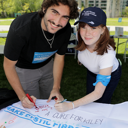 An older woman and a young woman who are volunteering for the Walk join arms and smile