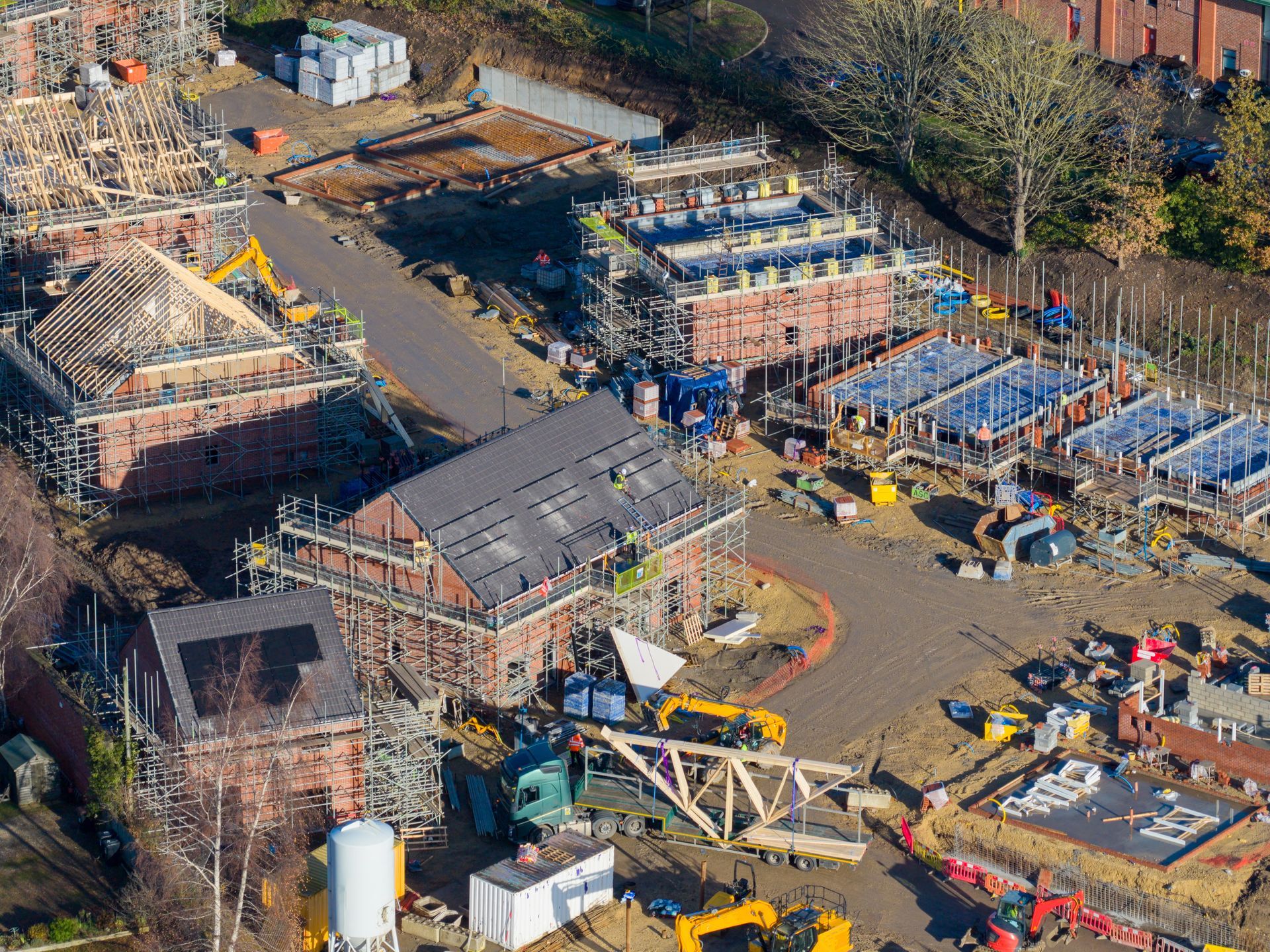 An aerial view of a residential construction site showing multiple houses in various stages of development. An aerial view of a residential construction site showing multiple houses in various stages of development.