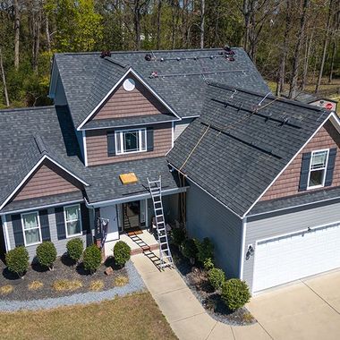 House with dark gray roof, brown accents, and a ladder leaning against it.