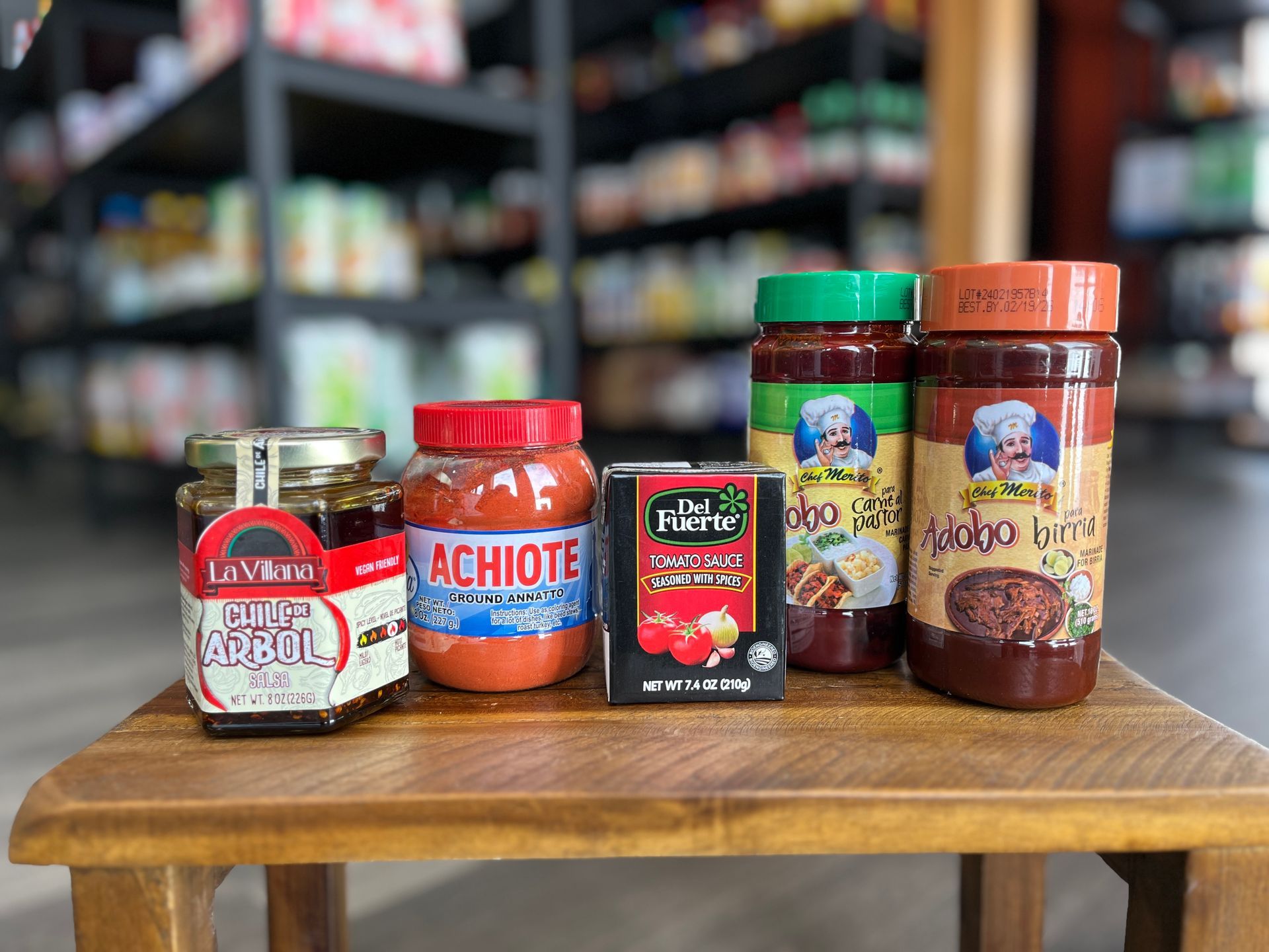 A wooden stool with a variety of sauces on it in a store.